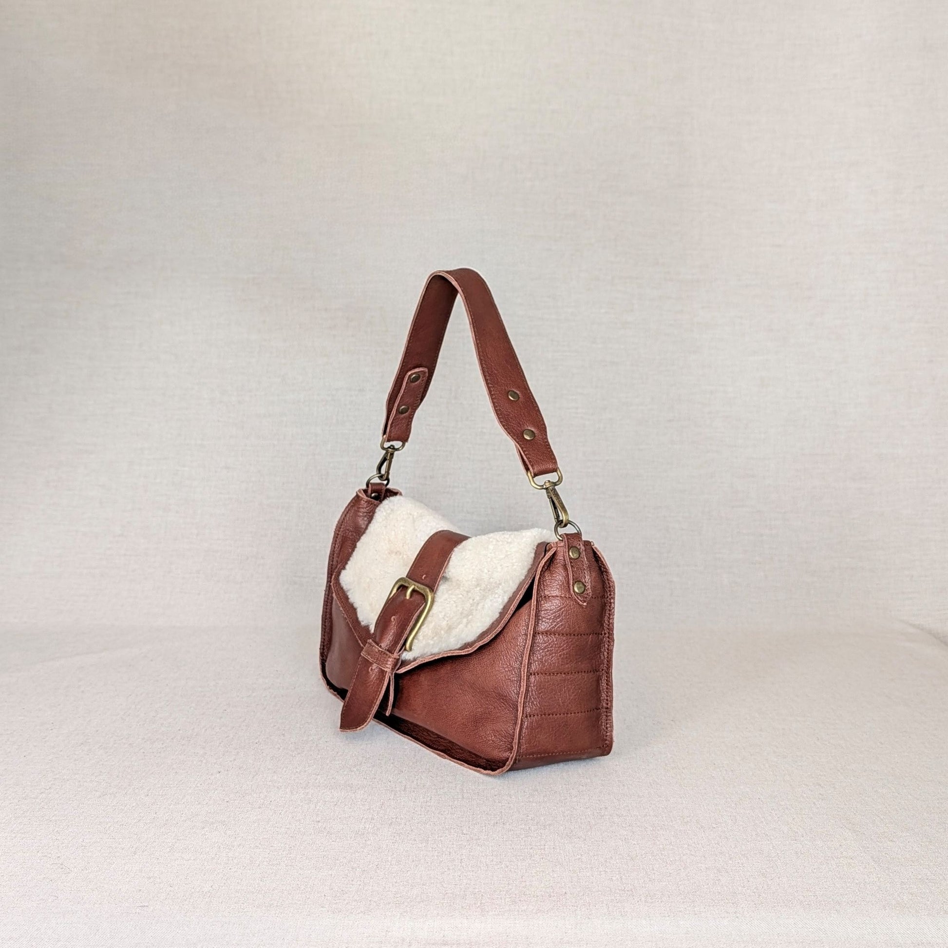 olso ADDY de napa de cordero Belice — solapa hair-on — bolso compacto con bandolera regulable — color marrón